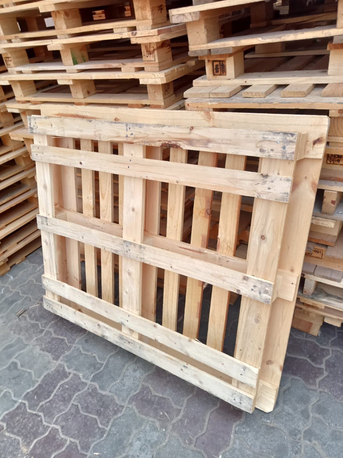 A newly built wooden pallet stood on edge, showing its deck boards, bearers and blocks