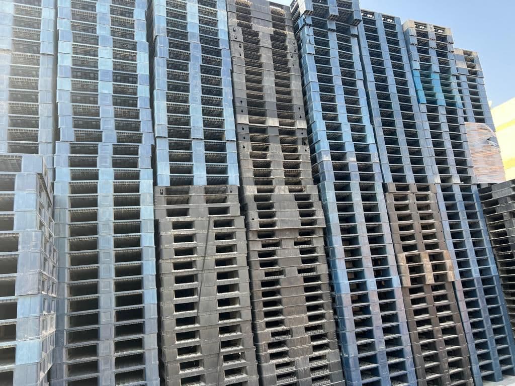 Stacks of used grey and black plastic pallets graded in the Sharjah yard